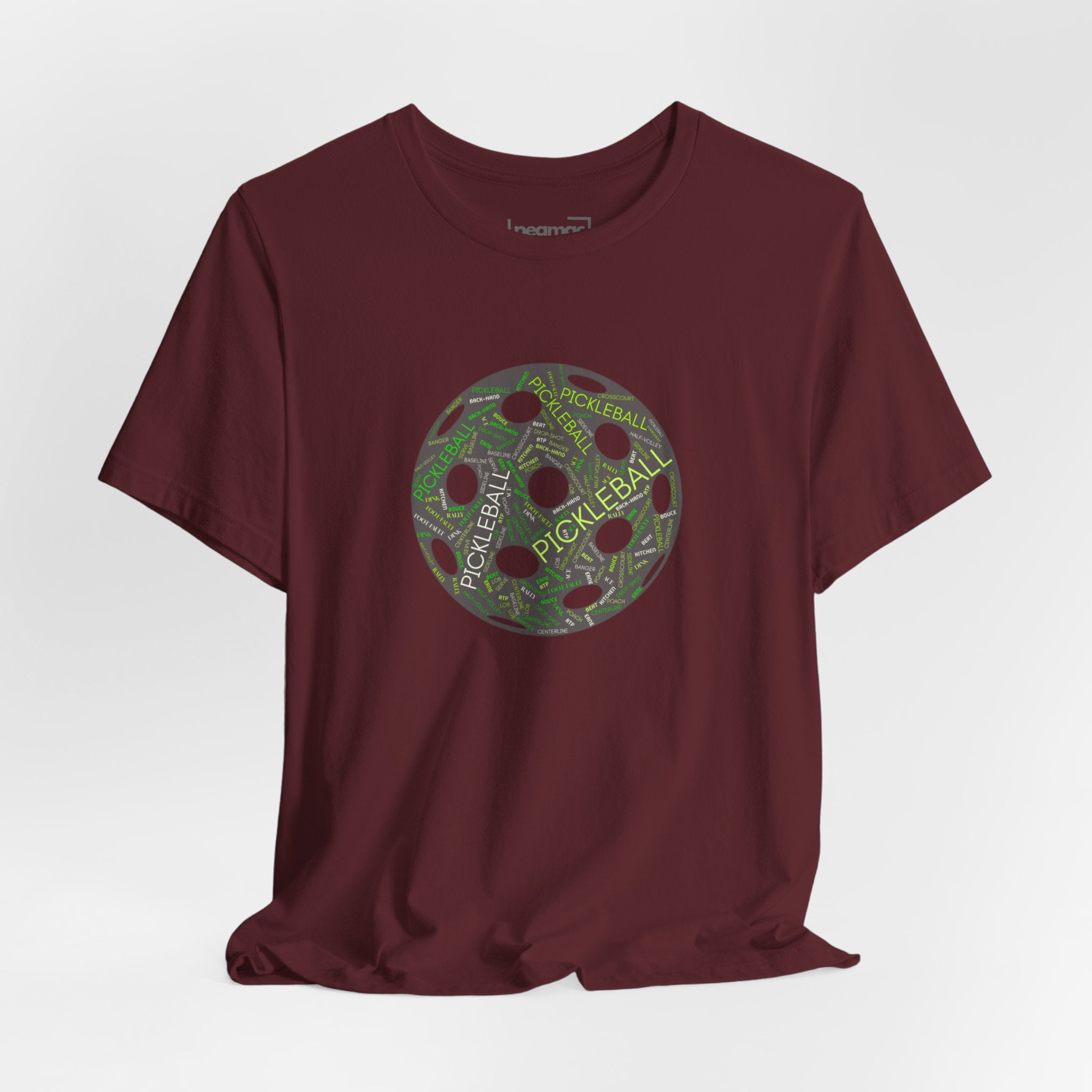 Pickleball Word Cloud T-Shirt featuring a pickleball-shaped graphic with words like dink, pickle, and kitchen on a casual tee.