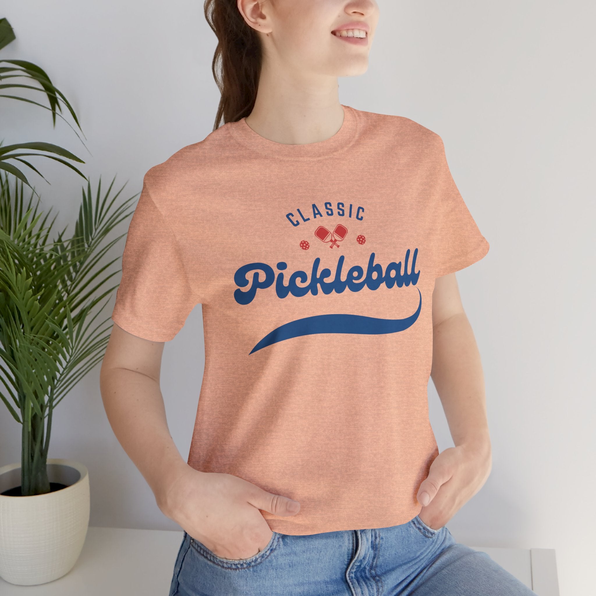 Red and blue pickleball T-shirt with script logo, featuring paddle and ball design, by Printify.