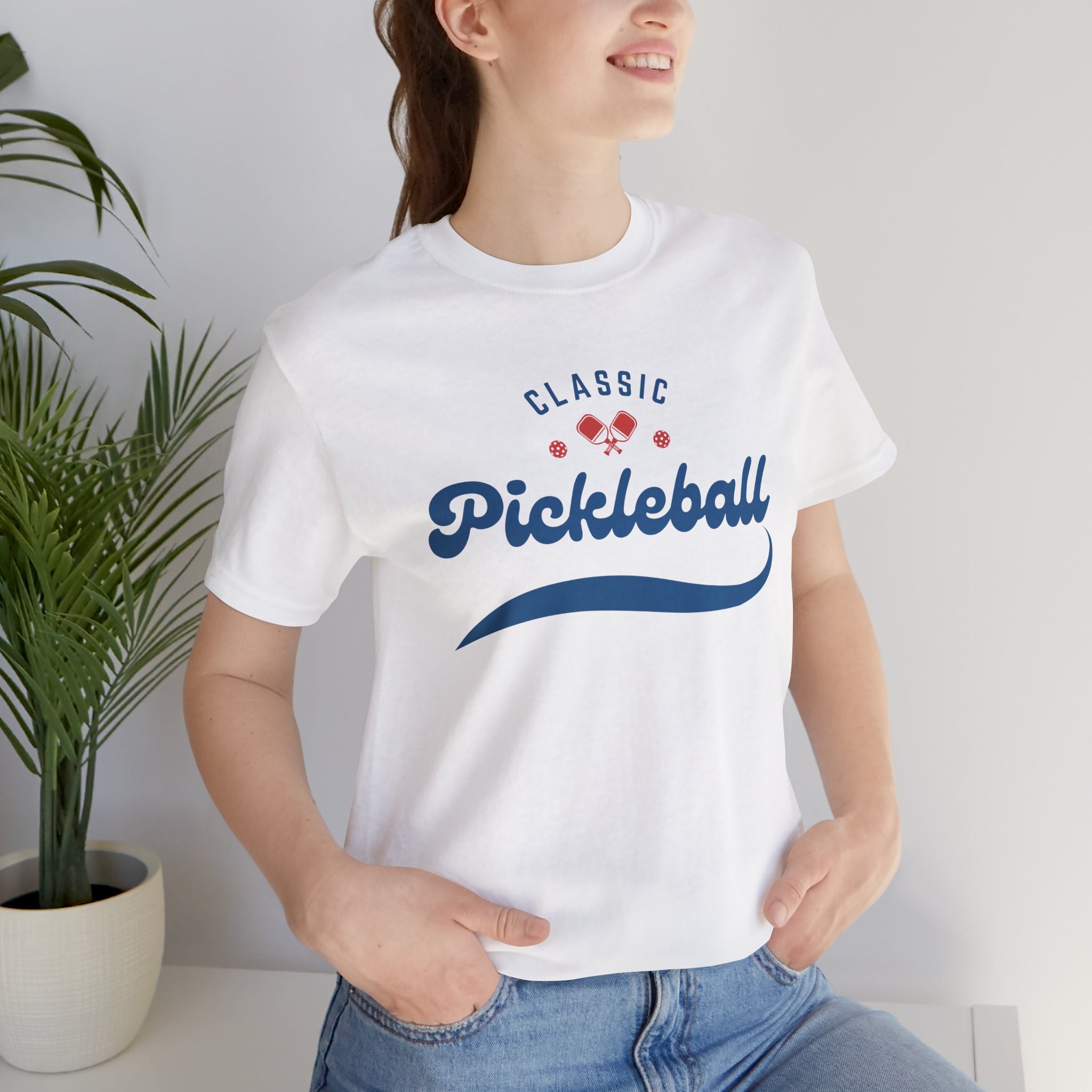 Red and blue pickleball script T-shirt featuring paddle and ball graphic, casual athletic wear by Printify
