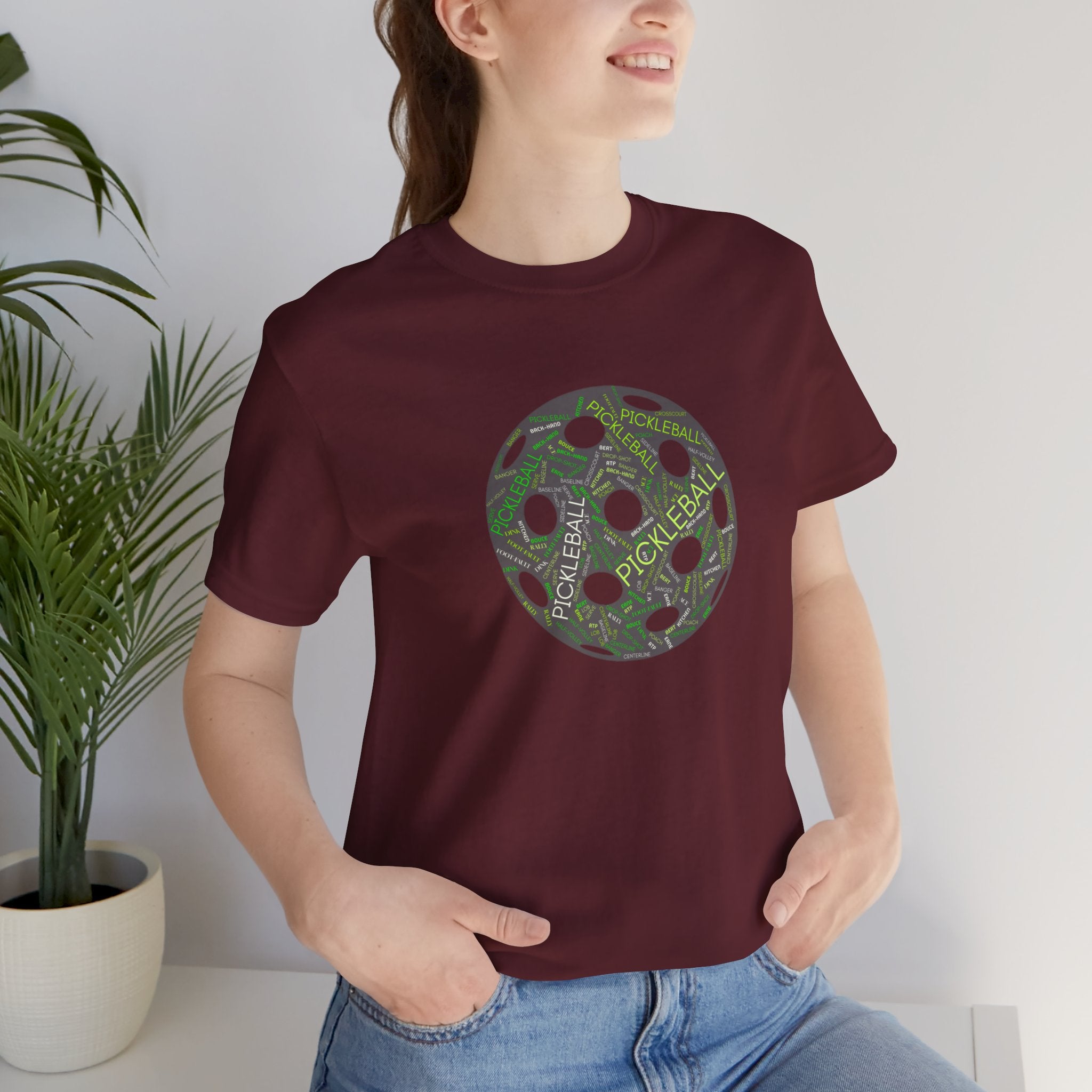 Pickleball Word Cloud T-shirt with pickleball-shaped graphic featuring words like dink, pickle, and kitchen on a casual tee.