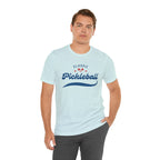 Red and blue pickleball script tee featuring paddle and ball design, casual cotton T-shirt by Printify.