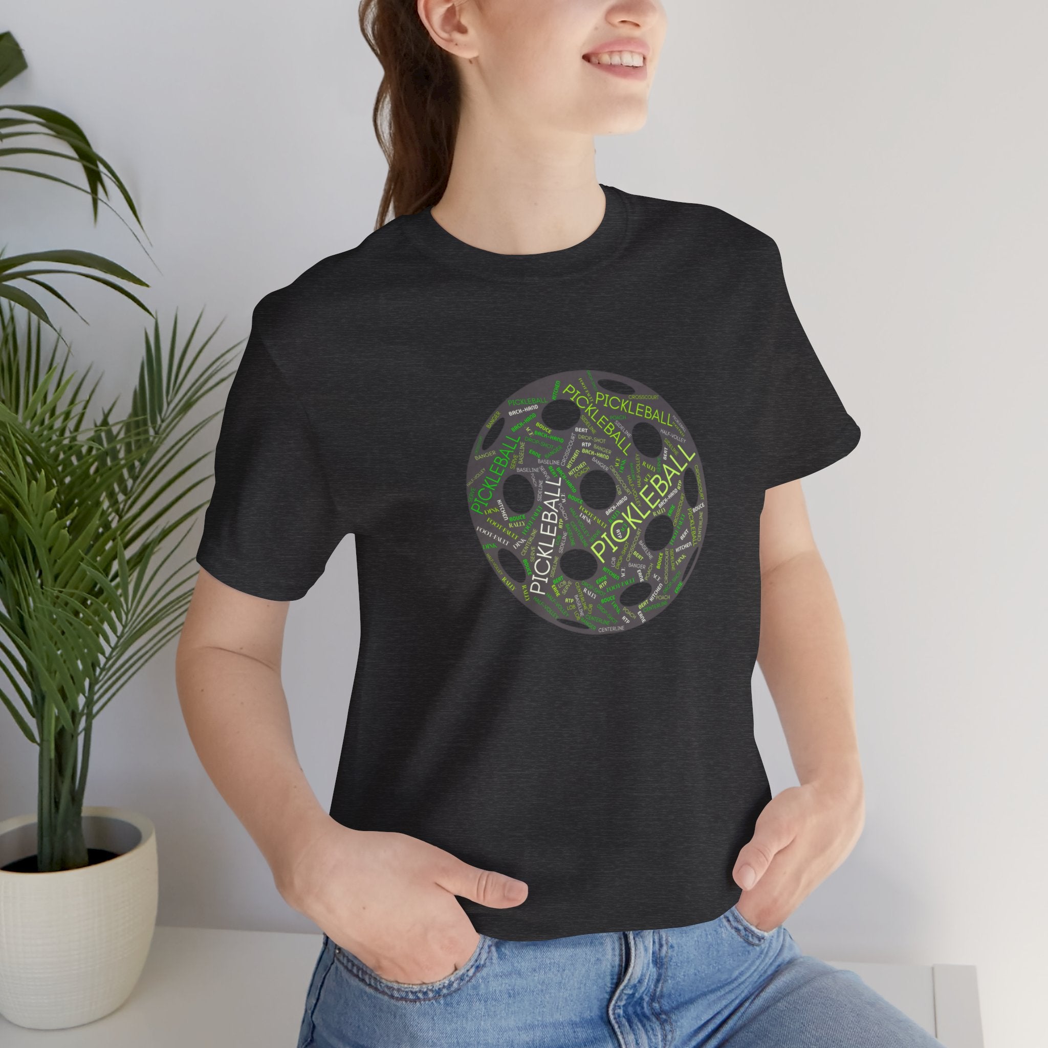 Pickleball Word Cloud T-Shirt with pickleball-shaped graphic and words like Dink, Pickle, and Kitchen, by Printify.