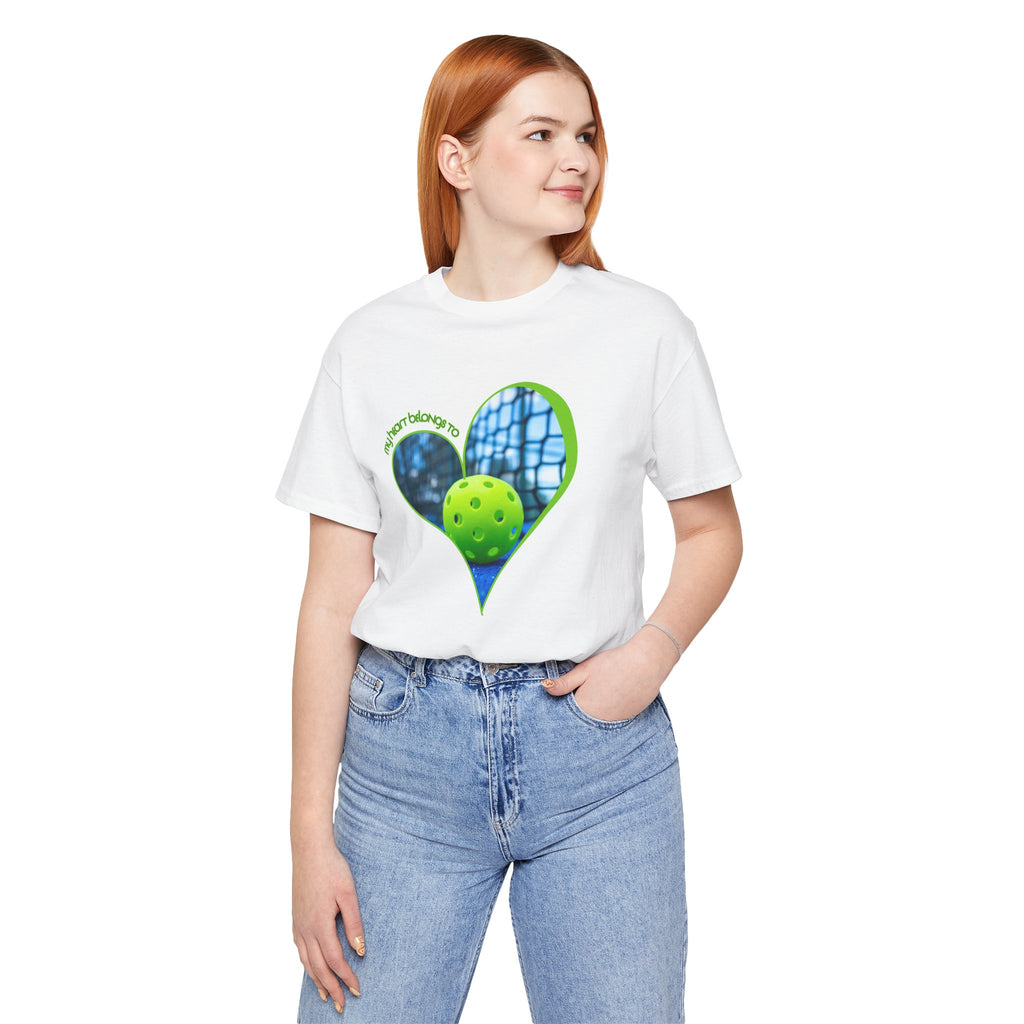 White Pickleball T-shirt with "My Heart Belongs to Pickleball" print, worn by a person playing pickleball outdoors.